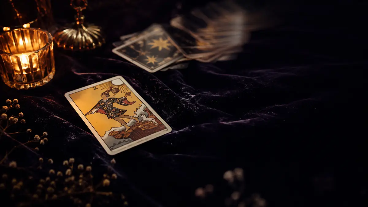 A single tarot card revealed face-up in warm candlelight on dark velvet for an instant online draw.